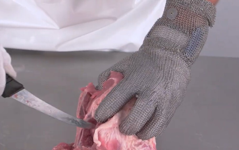 Metal mesh butcher gloves protecting hands during meat processing