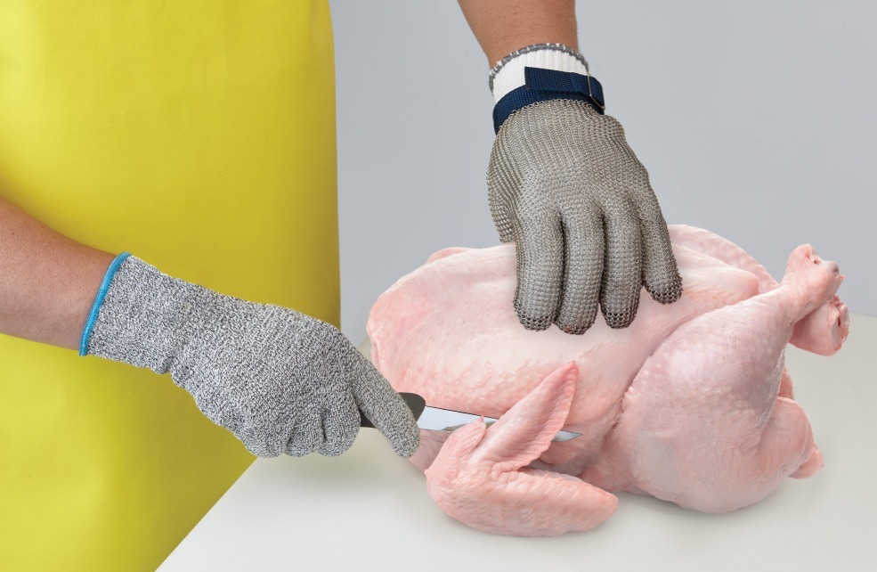 Worker using cut-resistant gloves in meat processing